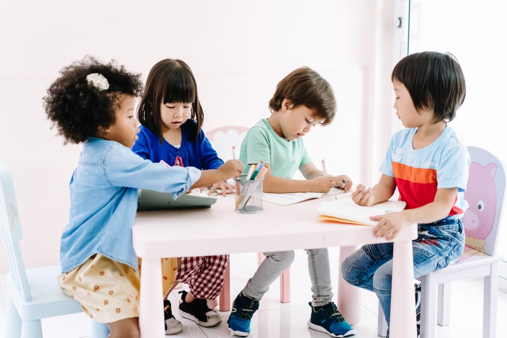 Young children of different backgrounds colouring together at a low activity table