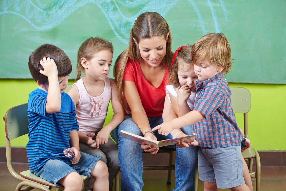 An educator reading a picture book to a small group of attentive young children